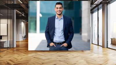 Handsome middle-eastern guy businessman posing next to office center Wall mural