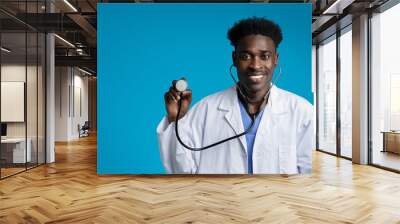 Handsome young african american doctor posing on blue, copy space Wall mural