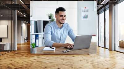 Handsome young Arab businessman working with laptop computer at his desk in office Wall mural