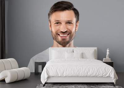 Handsome young caucasian man smiling at camera on grey Wall mural