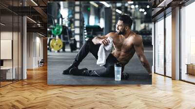 Handsome young muscular sportsman resting after workout Wall mural