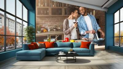 Happy african-american couple cooking and drinking red wine Wall mural