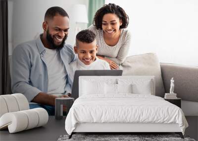 Happy african american family using laptop in living room Wall mural