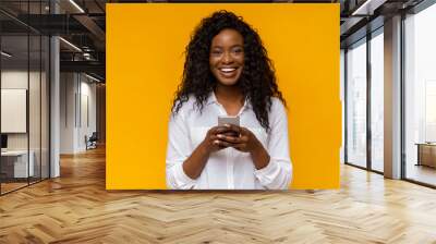 Happy african american girl using her smartphone Wall mural