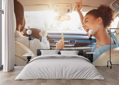 Happy afro couple driving in car and singing song Wall mural