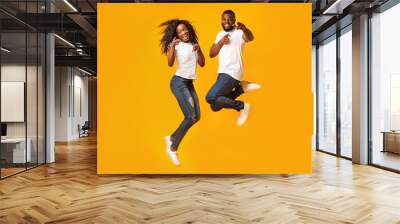 Happy afro couple is jumping in the air Wall mural