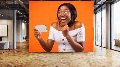 Happy Afro Girl Holding Cellphone Gesturing Yes, Orange Background, Panorama Wall mural