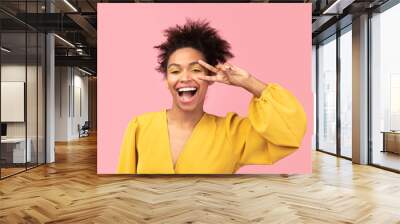 Happy afro girl showing v sign looking at camera Wall mural