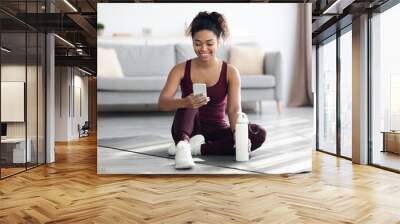 Happy athletic black woman using mobile phone while exercising Wall mural