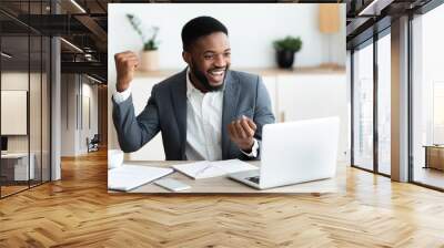 Happy black businessman rejoicing success at workplace in office Wall mural