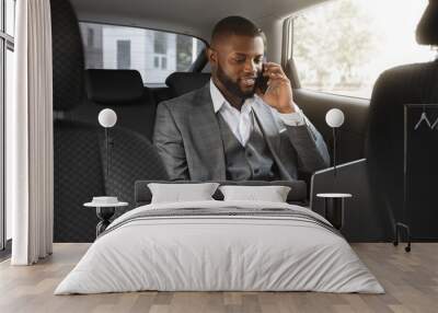 Happy black businessman talking on mobile phone in car Wall mural