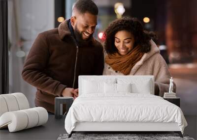 Happy black couple holding shopping bags looking inside Wall mural