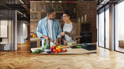 Happy black couple preparing salad in loft kitchen Wall mural