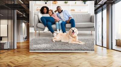 Happy black family sitting in living room with dog Wall mural