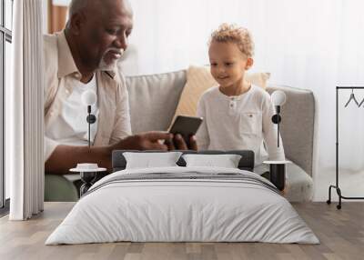 Happy Black Grandpa Showing Mobile Phone To Grandson At Home Wall mural