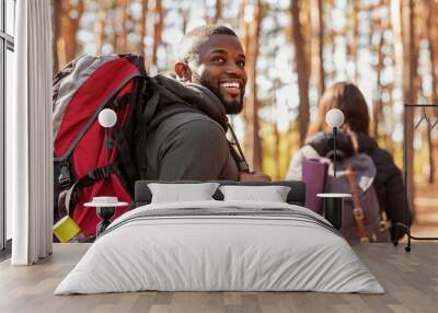 Happy black guy looking aside, hiking with girlfriend Wall mural