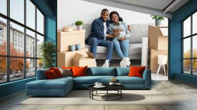 Happy Black Pregnant Couple Relaxing On Couch After Moving To New Apartment Wall mural