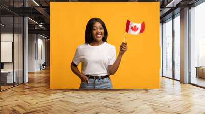 Happy black woman showing canadian flag on yellow Wall mural