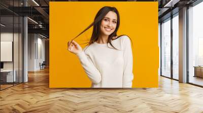 Happy brunette girl flirting and touching her long beautiful hair Wall mural