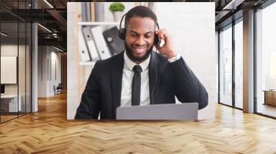 Happy business consultant with headset looking at laptop Wall mural