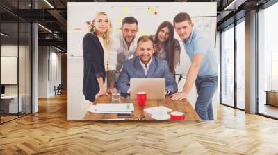 Happy business people team together near laptop in office Wall mural