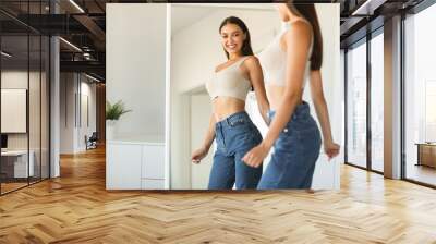 Happy caucasian lady enjoying her reflection in mirror, posing after successful weight loss near mirror Wall mural