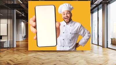 Happy chef man showing smartphone with white blank screen, recommending catering service or food delivery app Wall mural