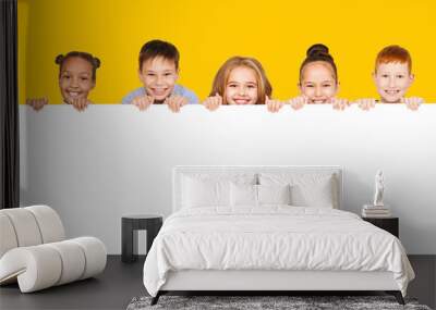 Happy children with empty board, yellow background Wall mural