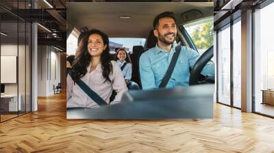 Happy european family of three riding car, traveling by automobile together, parents and daughter enjoying road trip Wall mural