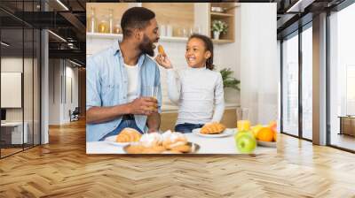 Happy family eating cookies and drinking juice at kitchen Wall mural