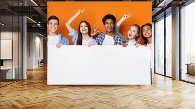 Happy friends holding empty banner, orange background Wall mural