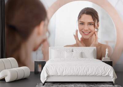 Happy girl enjoying her young smooth skin, looking at mirror Wall mural