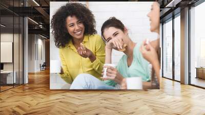 Happy girls drinking tea and eating sweets at home Wall mural