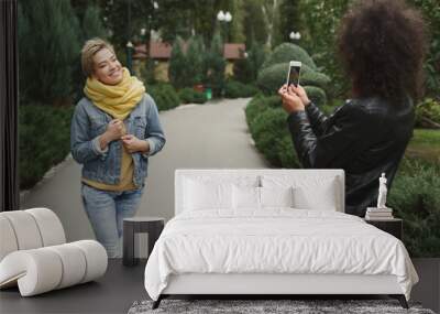 Happy girls with smartphone outdoors in the park Wall mural