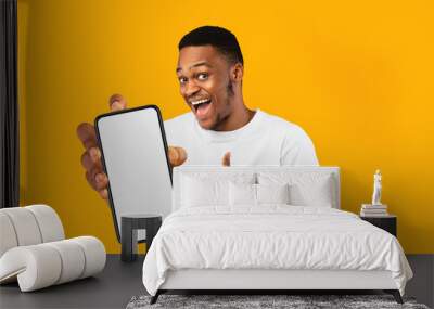 Happy handsome black man holding smartphone with empty screen Wall mural