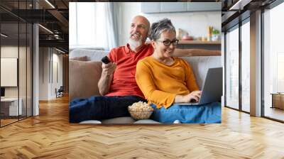 Happy loving elderly couple spending time together on couch at home Wall mural