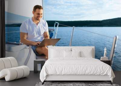 Happy Man On Yacht Sitting With Laptop Working On Sailboat Wall mural