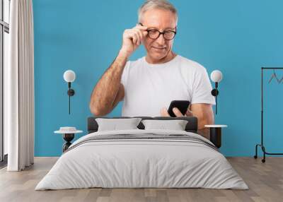 Happy mature man using his mobile phone at studio Wall mural