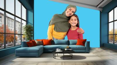 Happy Middle Eastern Mother Wearing Hijab Embracing Daughter, Blue Background Wall mural