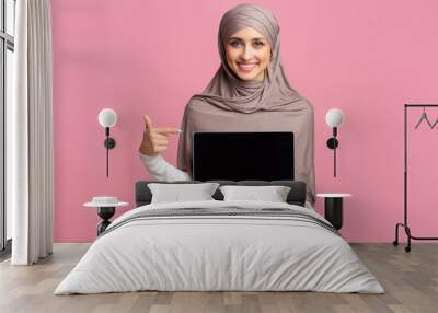 Happy muslim girl holding laptop with black screen in her hand Wall mural