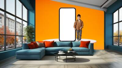 Happy positive schooler little boy standing by big smartphone Wall mural