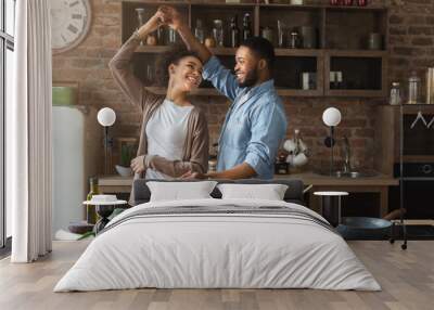 Happy romantic couple dancing in kitchen while cooking Wall mural