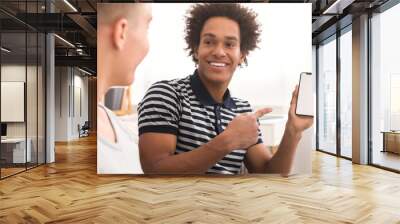 Happy teen boy showing mobile application to his friend Wall mural