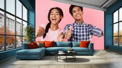 Happy teenage couple showing thumbs up, pink background Wall mural