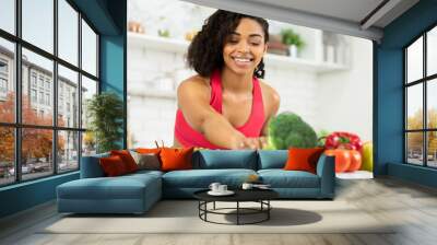 Happy young black woman preparing vegetable salad Wall mural