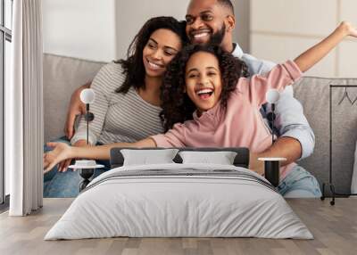 Happy young family watching television sitting on sofa Wall mural