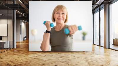 Home training concept. Strong senior woman doing exercises with dumbbells indoors Wall mural