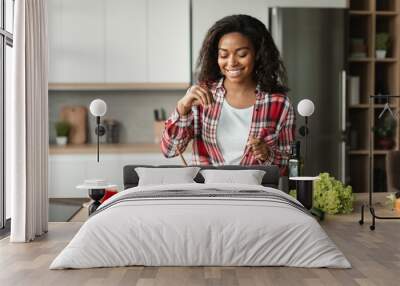 Homemade food and health care. Cheerful black young woman chef in casual salts salad from organic vegetables Wall mural