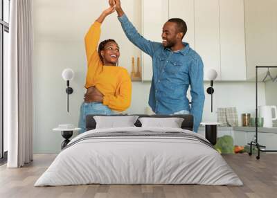 Joyful african american couple cooking and having fun, dancing and spending time in modern kitchen at home Wall mural