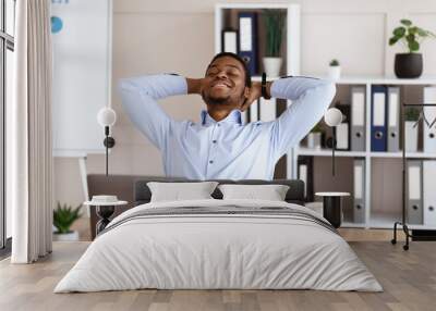 Joyful african american employee resting on his chair Wall mural